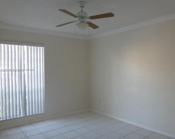 tiled spare room with crown molding and ceiling fan