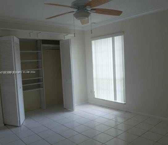 unfurnished bedroom featuring light tile patterned floors, a closet, ceiling fan, and crown molding