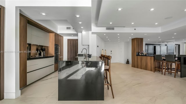 interior space with sink, a kitchen breakfast bar, double oven, and white cabinets