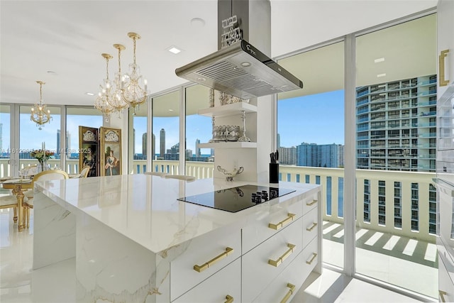 kitchen with a center island, a view of city, black electric stovetop, white cabinets, and island range hood