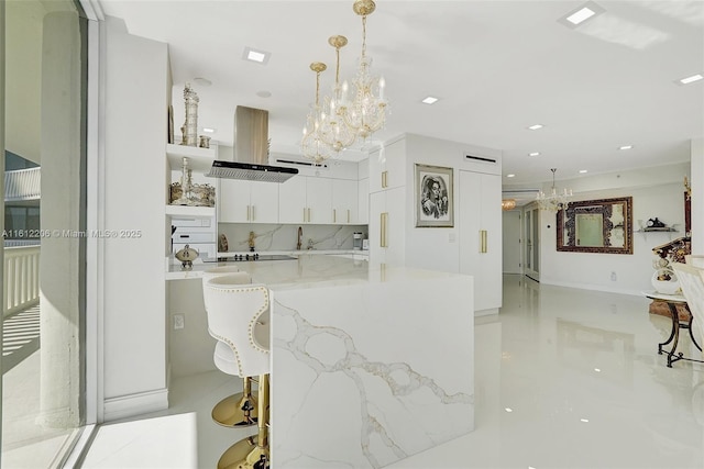 kitchen featuring a breakfast bar, hanging light fixtures, island exhaust hood, white cabinetry, and open shelves