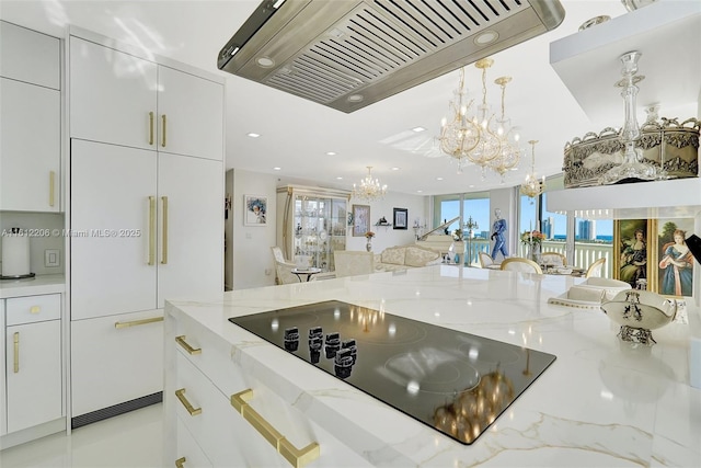 kitchen with a notable chandelier, premium range hood, black electric cooktop, and white cabinets