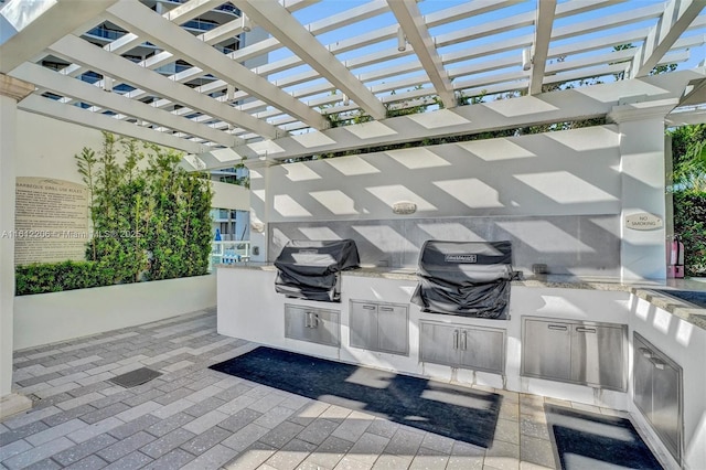 view of patio with exterior kitchen, grilling area, and a pergola