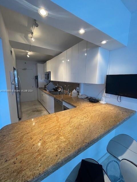 kitchen with white cabinetry, sink, stainless steel fridge, and kitchen peninsula