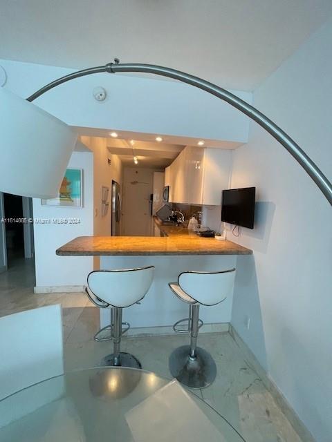 bar featuring a towering ceiling and stainless steel fridge