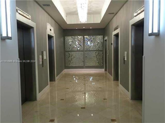 hallway with elevator and a raised ceiling