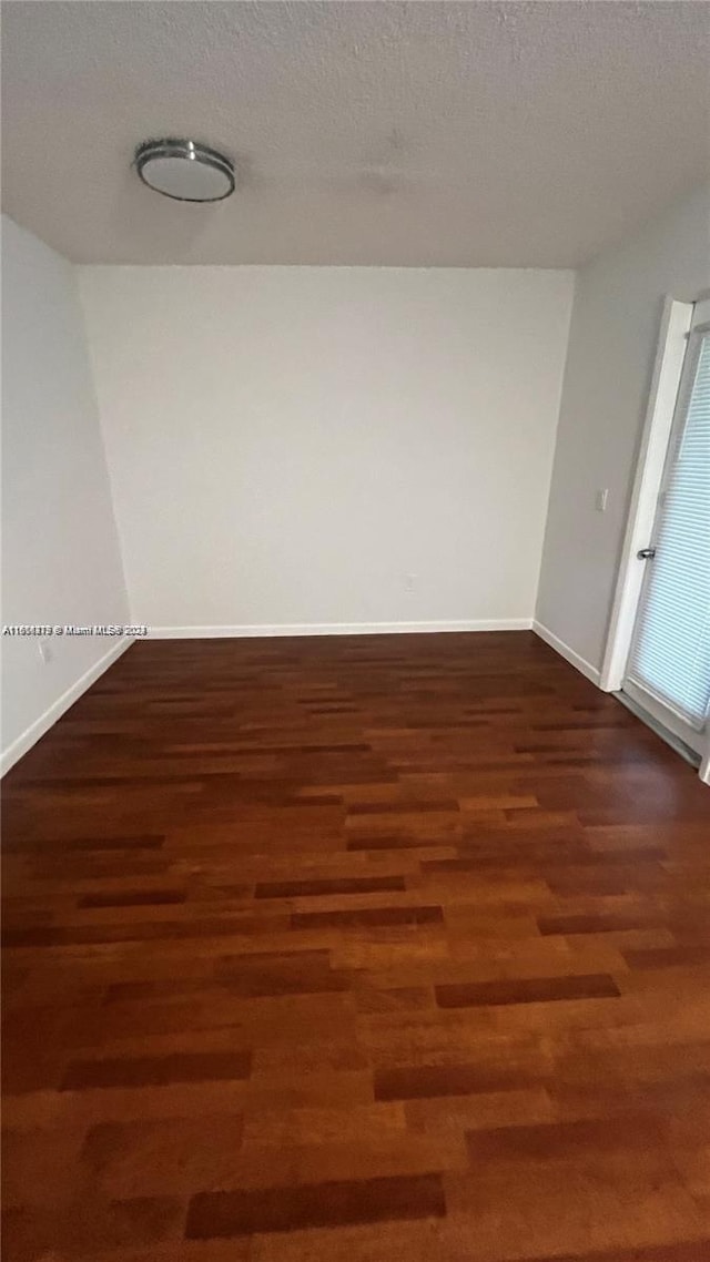 spare room with a textured ceiling and dark hardwood / wood-style floors