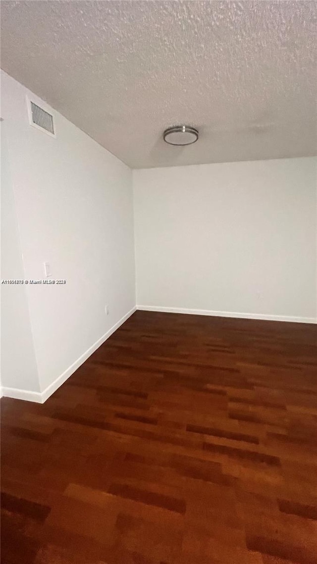 unfurnished room featuring dark hardwood / wood-style flooring and a textured ceiling