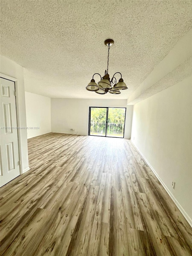 interior space with hardwood / wood-style flooring, a textured ceiling, and an inviting chandelier