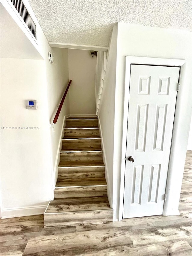 stairway featuring a textured ceiling and hardwood / wood-style flooring