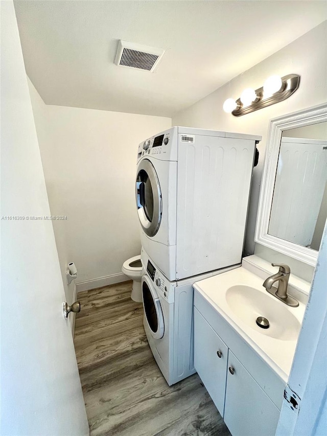 laundry area with light hardwood / wood-style floors, sink, and stacked washer and clothes dryer