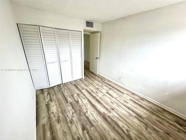 unfurnished bedroom featuring a closet, a textured ceiling, and light hardwood / wood-style floors