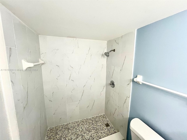 bathroom with a tile shower and toilet