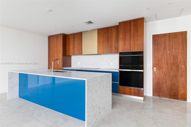 kitchen with a kitchen island with sink, black appliances, sink, decorative backsplash, and light tile patterned floors