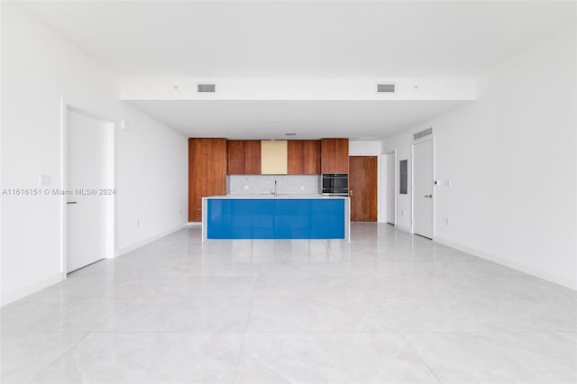 kitchen featuring decorative backsplash, a center island, light tile patterned floors, and sink