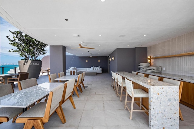 dining area with ceiling fan and a water view