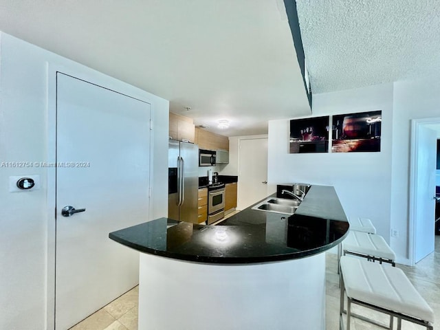 kitchen with white cabinets, sink, appliances with stainless steel finishes, a kitchen bar, and kitchen peninsula