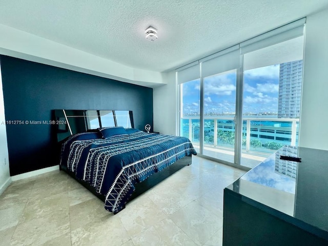 bedroom with access to exterior, expansive windows, and a textured ceiling