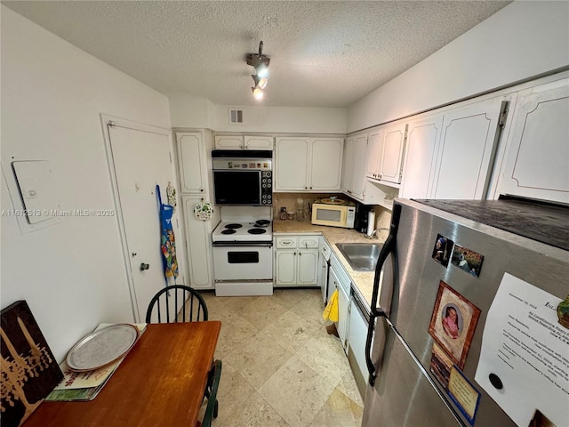 kitchen with white cabinets, a textured ceiling, white appliances, and sink