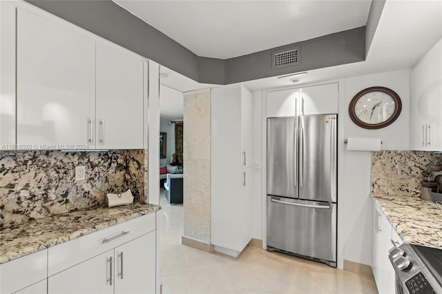 kitchen with light tile patterned flooring, white cabinetry, light stone counters, stainless steel appliances, and decorative backsplash