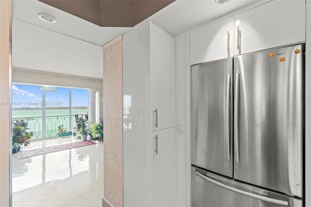 kitchen with stainless steel refrigerator, white cabinets, and a water view