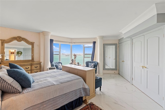 tiled bedroom with two closets, a water view, decorative columns, and crown molding