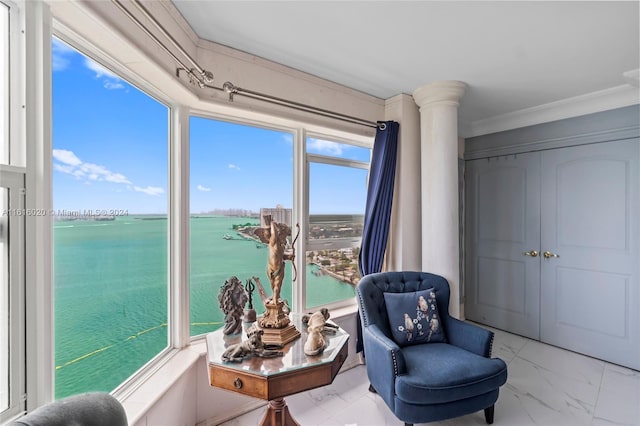 living area with ornamental molding and a water view