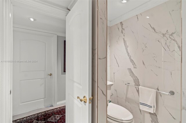 bathroom with crown molding, tile walls, and toilet