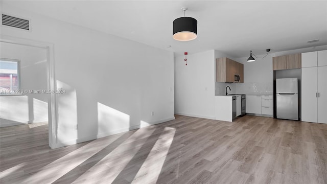 unfurnished living room with sink and light hardwood / wood-style flooring