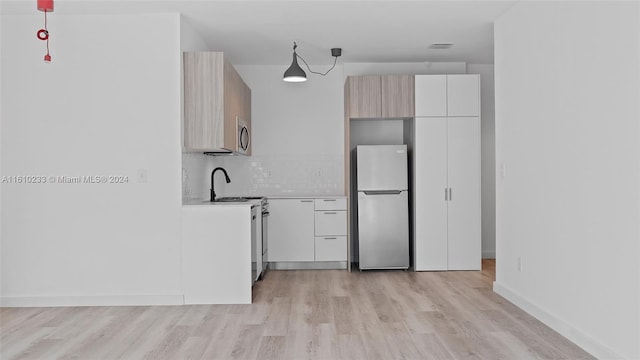 kitchen with stainless steel appliances, backsplash, and light hardwood / wood-style flooring