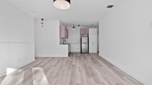 unfurnished living room with light hardwood / wood-style flooring and sink