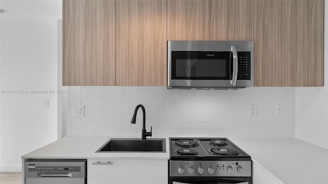 kitchen with stainless steel appliances, sink, light brown cabinetry, and backsplash