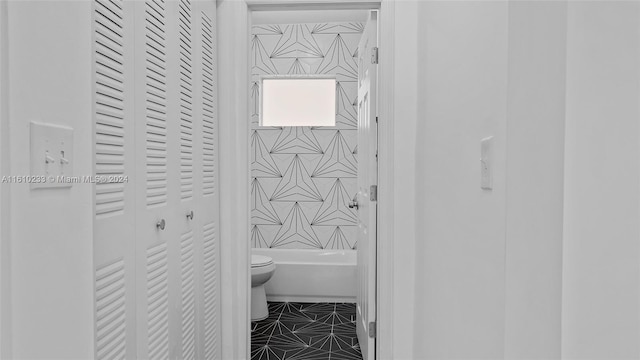 bathroom with toilet, tiled shower / bath, and tile patterned floors