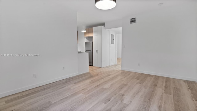 empty room with light wood-type flooring and electric panel