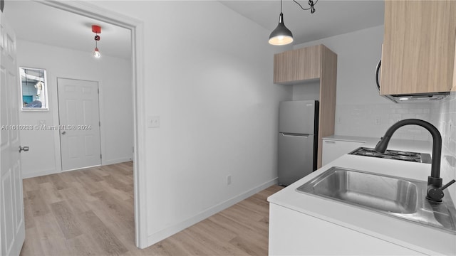 kitchen featuring stainless steel fridge, sink, pendant lighting, and light hardwood / wood-style flooring