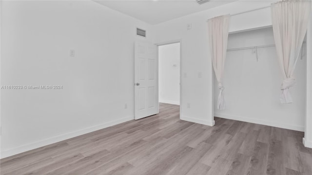 unfurnished bedroom with a closet and light hardwood / wood-style flooring