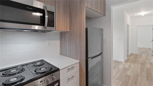 kitchen with white cabinetry, appliances with stainless steel finishes, light hardwood / wood-style floors, and tasteful backsplash