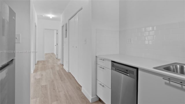 kitchen with tasteful backsplash, stainless steel dishwasher, white cabinetry, light hardwood / wood-style flooring, and fridge