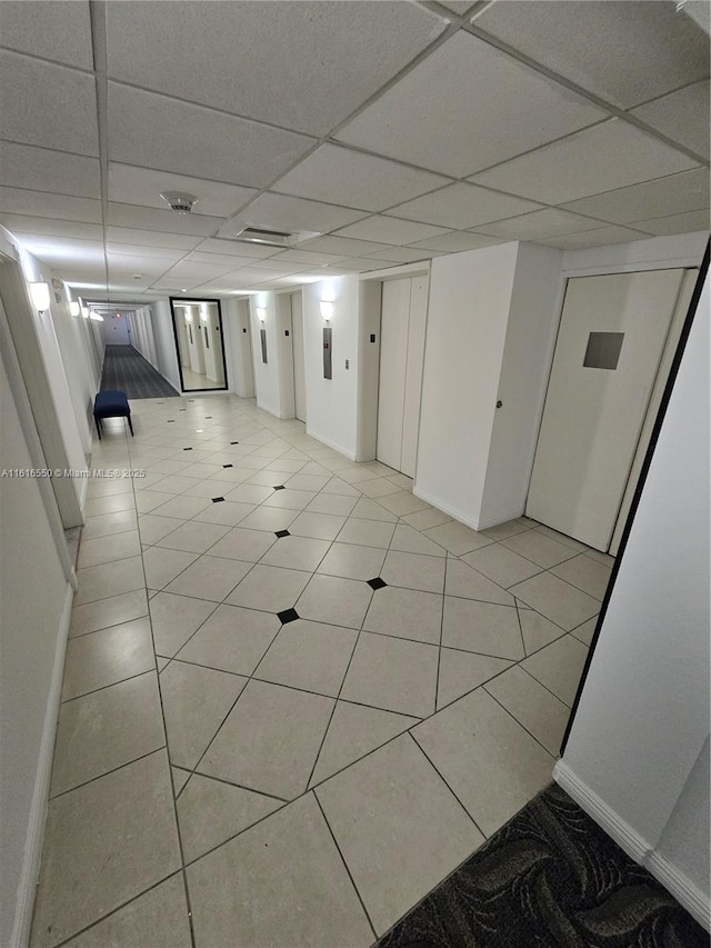 basement featuring a paneled ceiling and light tile patterned floors