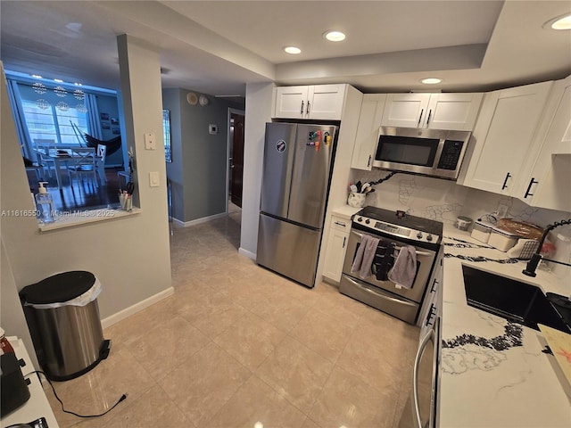 kitchen with backsplash, light stone countertops, white cabinets, and appliances with stainless steel finishes