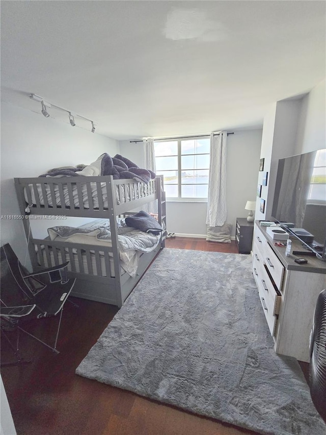 bedroom with track lighting and dark hardwood / wood-style flooring