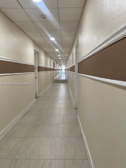 hall with a paneled ceiling