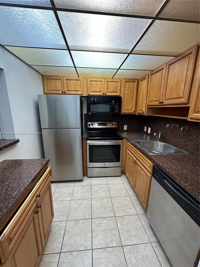 kitchen with light tile patterned floors, stainless steel appliances, tasteful backsplash, and sink