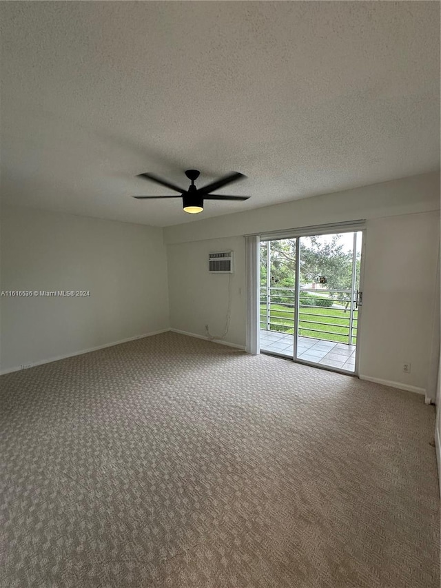 carpeted spare room featuring an AC wall unit, ceiling fan, and a textured ceiling