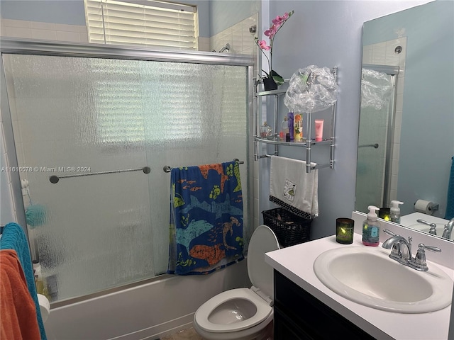 full bathroom featuring enclosed tub / shower combo, vanity, and toilet