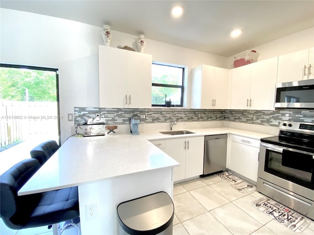 kitchen with sink, kitchen peninsula, tasteful backsplash, and stainless steel appliances