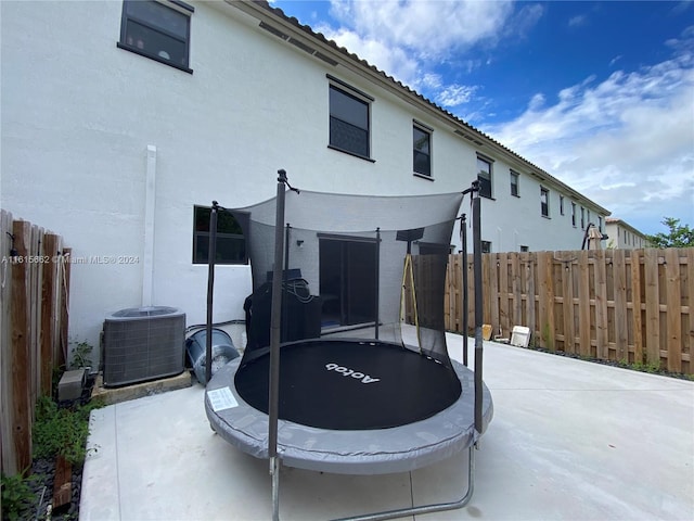 rear view of house with a trampoline, a patio area, and central AC unit