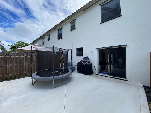 rear view of house featuring a patio and a trampoline