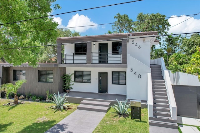 modern home featuring a front lawn and a balcony