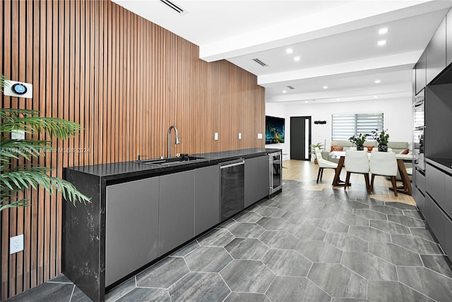 kitchen with wood walls, sink, stainless steel dishwasher, beamed ceiling, and wine cooler